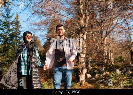 Ein glücklicher Paarreisender, der während der Wanderung zusammen mit Händen im Herbstwald spaziert, Abenteuer-Reise. Stockfoto