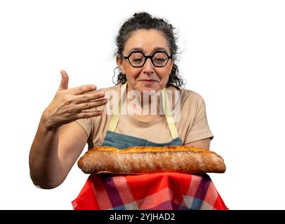 Bäckerfrau mit Schürze und Gläsern, die einen frisch gebackenen Brotlaib riechen Stockfoto