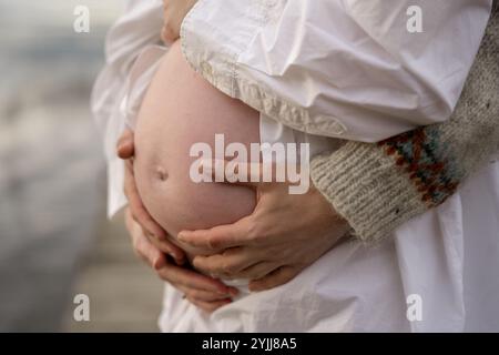 Nahaufnahme von Händen, die den schwangeren Bauch umarmen Stockfoto