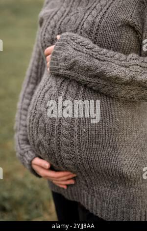 Schwangere Frau in Strickpullover, die Baby Bump hält Stockfoto