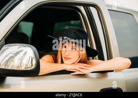 22 Jahre alte weiße Frau in schwarzem Hut, die im Truck sitzt Stockfoto