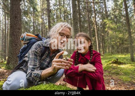 Kleines Mädchen und Großmutter, die Pilze im Wald anschauen Stockfoto