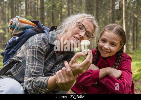 Kleines Mädchen und Großmutter untersuchen Pilze im Wald Stockfoto