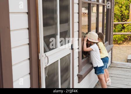 Kleine Mädchen schauen in das Fenster des historischen Gebäudes in Fort Steele Stockfoto