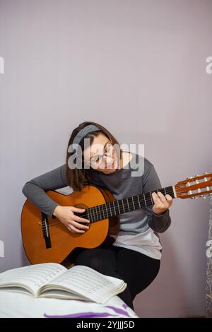 Musikerin, die klassische Gitarre übt und Notizen aus Notenblättern zu Hause liest, genießt ihr Hobby Stockfoto