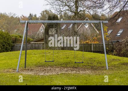 Leere Schaukeln in einem ruhigen Park an einem Herbsttag, die einen ruhigen Moment mit gefallenen Blättern und nostalgischem Flair festhalten. Gronau, Deutschland. Stockfoto