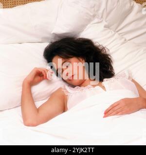 Eine junge Frau drinnen im Bett, die schläft. Stockfoto