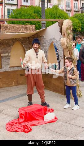 Ein Zauberer, der einen Zaubertrick mit einem kleinen Jungen aus dem Publikum vorführt, der während der El Cid Fiestas Plaza Mayor Burgos Castile und Leon Spain assistiert Stockfoto