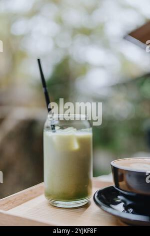 Japanischer Eismatcha Latte, grüner Tee mit Milch, Sojamilch, mit Strohhalm im Glas. Café im Freien Stockfoto