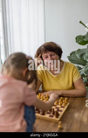 Glückliche Großmutter und Enkelin spielen Schach und schaffen zusammen wertvolle Erinnerungen. Hochwertige Fotos Stockfoto