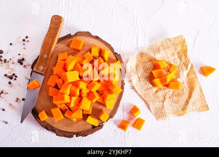 Rohe Kürbiswürfel auf Holzbrett Stockfoto