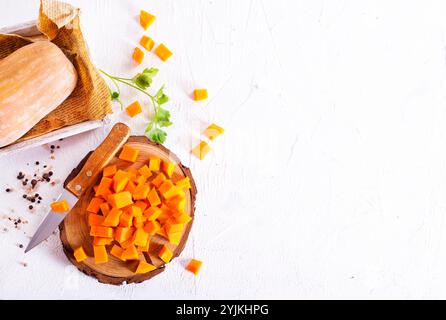 Rohe Kürbiswürfel auf Holzbrett Stockfoto