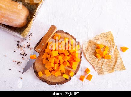 Rohe Kürbiswürfel auf Holzbrett Stockfoto