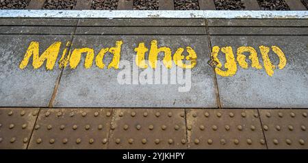 Gelb, denken Sie an die Lückenwarnung, die auf dem Bahnsteig gemalt ist Stockfoto