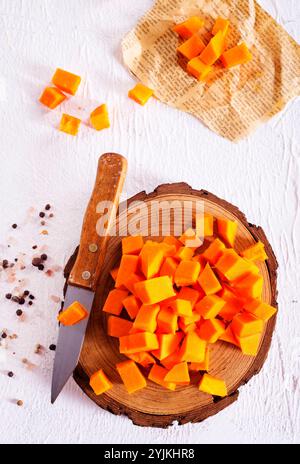 Rohe Kürbiswürfel auf Holzbrett Stockfoto