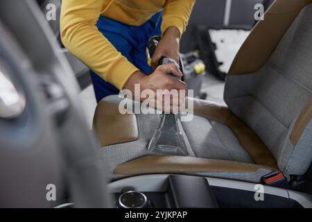 Mann Arbeiter, der den Innenraum des Autos mit einem Staubsauger reinigt Stockfoto