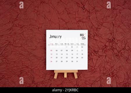 Januar 2025 Kalender auf rotem zerknittertem Papierhintergrund. Direkt darüber. Flache Lagen. Stockfoto