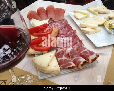 Ein Glas Rotwein serviert mit einer Platte mit italienischen Vorspeisen einschließlich Bruschetta, Wurstwaren und Käse Stockfoto