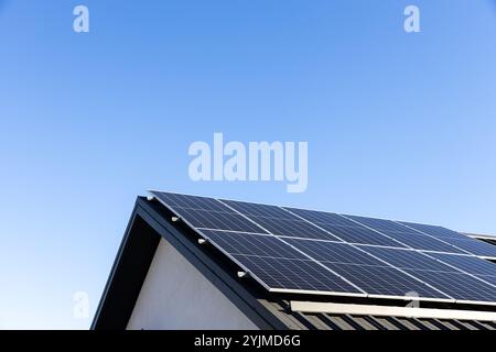 Modernes Haus mit Solarpaneelen, eigenständiges Photovoltaik-Anlagensystem auf dem Dach des Haushaltsblechs. Blauer Hintergrund. Saubere Alternative en Stockfoto