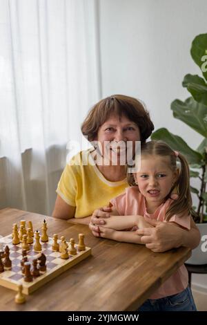 Konzentriert, aber fröhlich, lachen Großmutter und Enkelin gemeinsam Schach. Hochwertige Fotos Stockfoto