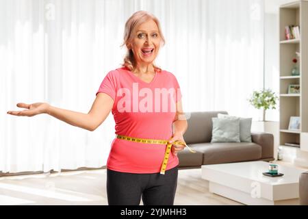 Glückliche reife Frau, die ihre Taille misst Stockfoto