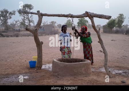 Ségou, Mali - März 13 2022:Ein Dorf in Afrika. Afrikanische Frauen, die Wasser aus dem lokalen Brunnen ziehen. Stockfoto