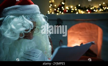 Der Weihnachtsmann liest Weihnachtsbriefe vor dem Kamin Stockfoto