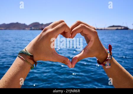 Ein Herz, geformt mit den Händen einer Frau mitten im Meer. Stockfoto