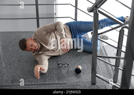 Verwundeter Mann auf Treppen im Gebäude nach dem Sturz. Gefährlicher Unfall Stockfoto