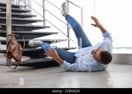 Verletzter Mann auf dem Boden im Gebäude nach dem Sturz von der Treppe. Gefährlicher Unfall Stockfoto