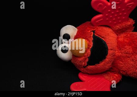 Glückliches Plüschtier Elmo auf schwarzem Hintergrund. Ein roter Muppet aus der Sesamstraße. Elmos Welt. Stockfoto