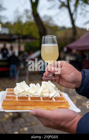 Weinfest in Schengen, Luxemburg, französischen oder luxemburgischen Waffeln mit Schlagsahne und einem Glas Jungwein, der im Herbst im Freien gegessen wird Stockfoto
