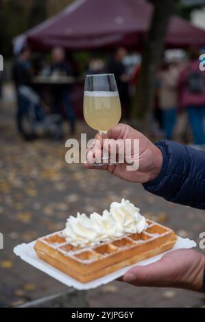 Weinfest in Schengen, Luxemburg, französischen oder luxemburgischen Waffeln mit Schlagsahne und einem Glas Jungwein, der im Herbst im Freien gegessen wird Stockfoto