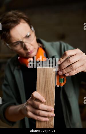 Ein engagierter Zimmermann konzentriert sich darauf, Holz genau zu messen und handwerkliches Können und Können zu demonstrieren. Stockfoto