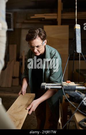 Ein erfahrener Zimmermann konzentriert sich auf die präzise Holzherstellung in einer ansprechenden Werkstattatmosphäre. Stockfoto