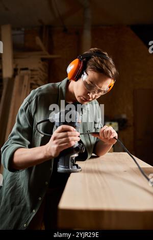 Ein gelernter Zimmermann arbeitet fleißig mit Elektrowerkzeugen an Holz, umhüllt von Kreativität und Konzentration in der Werkstatt. Stockfoto