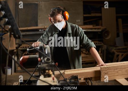 Eine gelernte Schreinerin arbeitet fleißig mit Holz und demonstriert Handwerkskunst und Aufmerksamkeit in ihrer Werkstatt. Stockfoto