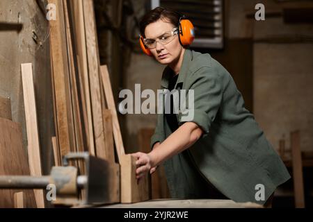 Eine geschickte Zimmermannin konzentriert sich intensiv auf die Holzarbeit in ihrer geschäftigen Werkstatt. Stockfoto