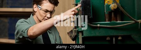In einer lebendigen Werkstatt konzentriert sich eine gelernte Zimmermannin intensiv auf die Bedienung von Holzbearbeitungsmaschinen. Stockfoto