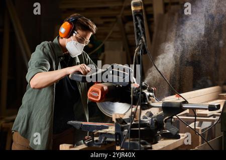In einer viel beschäftigten Werkstatt konzentriert sich eine Zimmermannin intensiv auf ihre Holzarbeit und zeigt handwerkliches Können und Präzision. Stockfoto