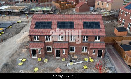 Das Dach einer Reihe neuer Häuser auf einer im Bau befindlichen Baustelle mit integriertem Dach oder in-Dach-Solarpaneelen für billig und nachhaltig Stockfoto