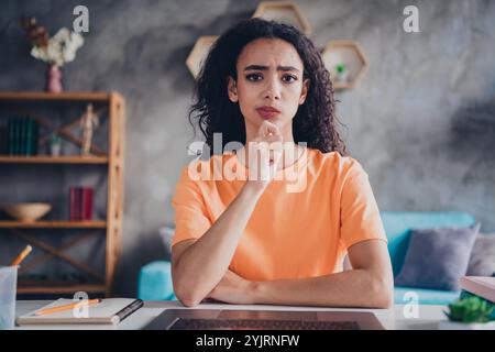 Nachdenkliche junge Frau, die Ideen nachdenkt, während sie zu Hause mit Stift in der Hand studiert, umgeben von einer gemütlichen Inneneinrichtung Stockfoto