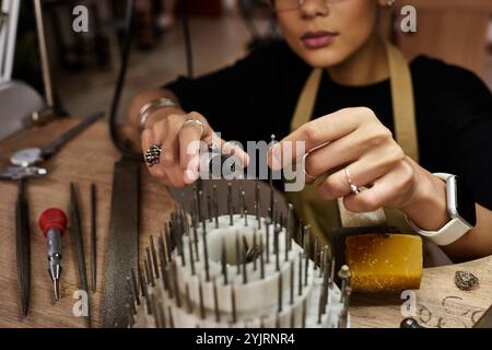 Ein erfahrener Handwerker, der in einer gut ausgestatteten Werkstatt sorgfältig wunderschöne Schmuckstücke herstellt. Stockfoto