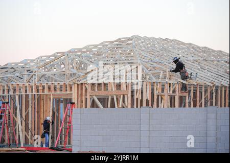 Apache Junction, Arizona, USA. November 2024. Der Boom des Wohnungsbaus im Pinal County, Arizona, verwandelt einst dünn besiedelte Gebiete schnell in neue Wohnsiedlungen. Bauarbeiter arbeiten lange Zeit, um die steigende Nachfrage nach erschwinglichem Wohnraum zu befriedigen, da sich die Unterteilungen erweitern, um der wachsenden Bevölkerung des Countys gerecht zu werden. Die Entwickler verweisen auf Arizonas starkes Wirtschaftswachstum und relativ erschwingliches Land in Pinal als Schlüsselfaktoren. Projekte versprechen eine Mischung aus Einfamilienhäusern, Stadthäusern und Annehmlichkeiten, um lokale und außerstaatliche Käufer anzuziehen. (Kredit-Imag Stockfoto