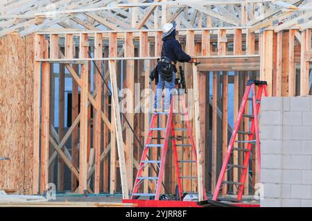 Apache Junction, Arizona, USA. November 2024. Der Boom des Wohnungsbaus im Pinal County, Arizona, verwandelt einst dünn besiedelte Gebiete schnell in neue Wohnsiedlungen. Bauarbeiter arbeiten lange Zeit, um die steigende Nachfrage nach erschwinglichem Wohnraum zu befriedigen, da sich die Unterteilungen erweitern, um der wachsenden Bevölkerung des Countys gerecht zu werden. Die Entwickler verweisen auf Arizonas starkes Wirtschaftswachstum und relativ erschwingliches Land in Pinal als Schlüsselfaktoren. Projekte versprechen eine Mischung aus Einfamilienhäusern, Stadthäusern und Annehmlichkeiten, um lokale und außerstaatliche Käufer anzuziehen. (Kredit-Imag Stockfoto