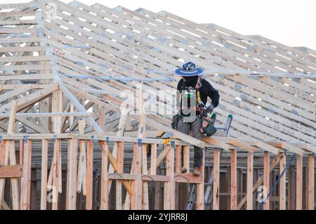 Apache Junction, Arizona, USA. November 2024. Der Boom des Wohnungsbaus im Pinal County, Arizona, verwandelt einst dünn besiedelte Gebiete schnell in neue Wohnsiedlungen. Bauarbeiter arbeiten lange Zeit, um die steigende Nachfrage nach erschwinglichem Wohnraum zu befriedigen, da sich die Unterteilungen erweitern, um der wachsenden Bevölkerung des Countys gerecht zu werden. Die Entwickler verweisen auf Arizonas starkes Wirtschaftswachstum und relativ erschwingliches Land in Pinal als Schlüsselfaktoren. Projekte versprechen eine Mischung aus Einfamilienhäusern, Stadthäusern und Annehmlichkeiten, um lokale und außerstaatliche Käufer anzuziehen. (Kredit-Imag Stockfoto