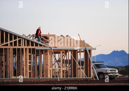 Apache Junction, Arizona, USA. November 2024. Der Boom des Wohnungsbaus im Pinal County, Arizona, verwandelt einst dünn besiedelte Gebiete schnell in neue Wohnsiedlungen. Bauarbeiter arbeiten lange Zeit, um die steigende Nachfrage nach erschwinglichem Wohnraum zu befriedigen, da sich die Unterteilungen erweitern, um der wachsenden Bevölkerung des Countys gerecht zu werden. Die Entwickler verweisen auf Arizonas starkes Wirtschaftswachstum und relativ erschwingliches Land in Pinal als Schlüsselfaktoren. Projekte versprechen eine Mischung aus Einfamilienhäusern, Stadthäusern und Annehmlichkeiten, um lokale und außerstaatliche Käufer anzuziehen. (Kredit-Imag Stockfoto