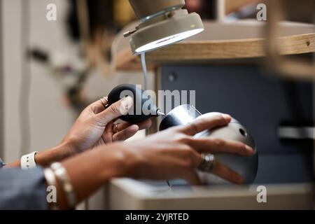 Ein Handwerker konzentriert sich auf die Herstellung von exquisitem Schmuck mit Präzisionswerkzeugen in einer gemütlichen Werkstatt. Stockfoto