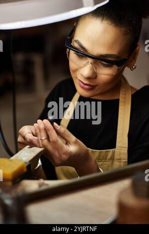 Die talentierte Handwerkerin kreiert atemberaubende Schmuckstücke und konzentriert sich auf ihre komplizierte Arbeit mit Leidenschaft. Stockfoto