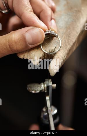 Handwerkskunst glänzt, wenn die Hände in einer Werkstatt akribisch an einem funkelnden Ring arbeiten. Stockfoto